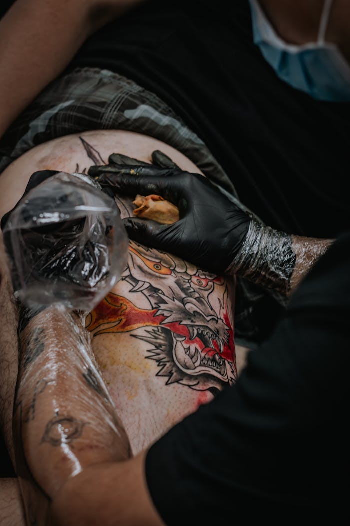 Close-up of tattoo artist creating a dragon tattoo in a studio setting.