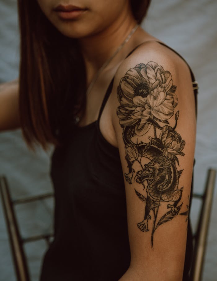 Side view of crop anonymous female with picture of dragon and flower on hand